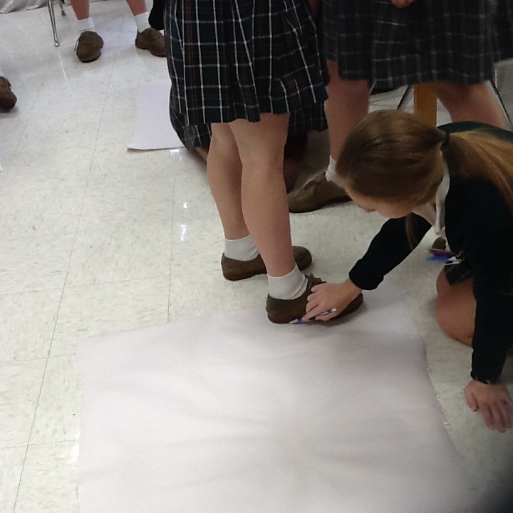 Female student traces the foot of her classmate. 